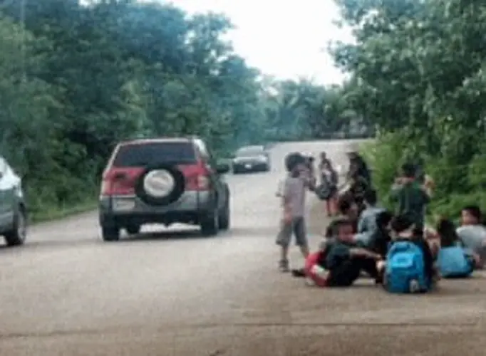 Kids wait in middle of intersection with no bus shelter