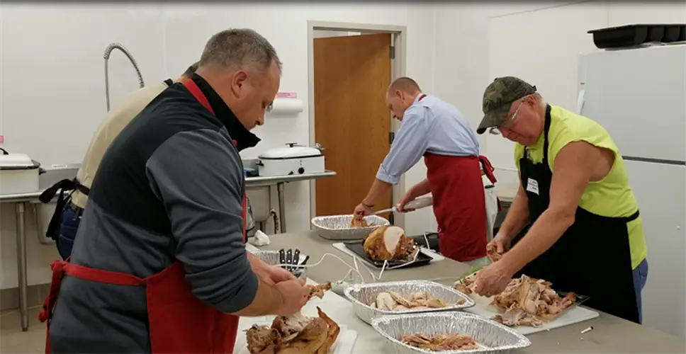 Manufacturing Employees Wield Electric Carving Knives, to Trim Turkeys for Holiday Meal