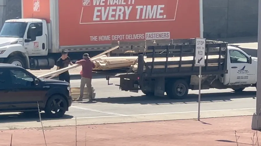 Men reload lumber in Highway 75 traffic